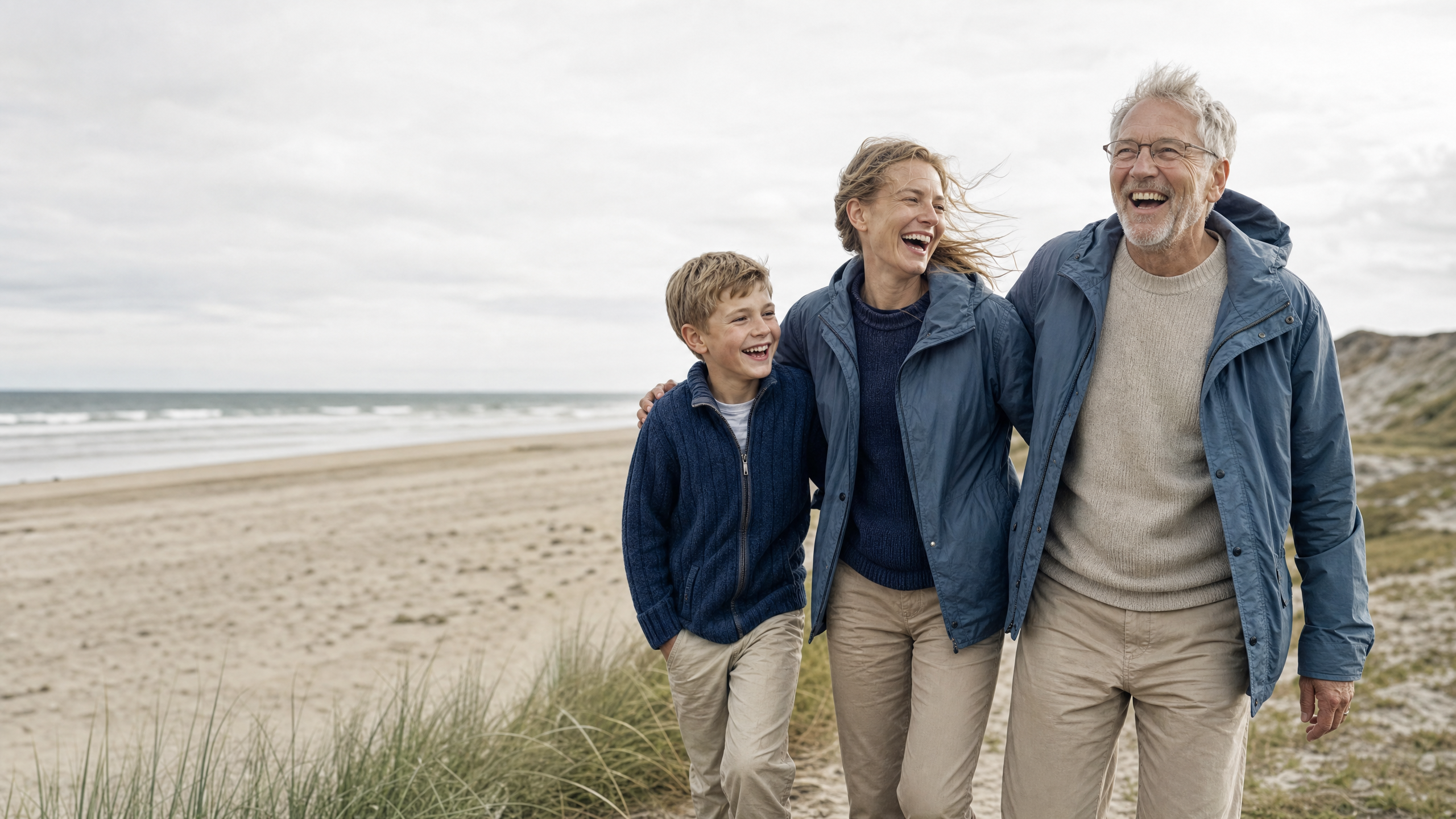 Tre generationer griner sammen på stranden ved Vesterhavet
